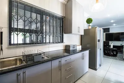a kitchen with a sink and a refrigerator at Patimo Opulent Accommodation -Pretoria Mayville,Gezina in Pretoria