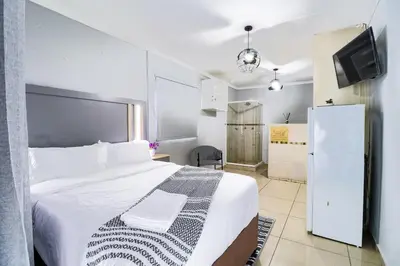 a bedroom with a white bed and a tv at Patimo Opulent Accommodation -Pretoria Mayville,Gezina in Pretoria