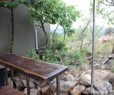 a wooden bench sitting on top of a pile of rocks at Luxury Treehouse on Bronberg Ridge in Tierpoort