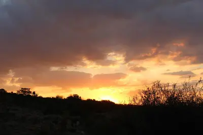a sunset over a hill with the sun setting at Luxury Treehouse on Bronberg Ridge in Tierpoort