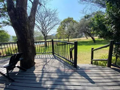 a wooden walkway with a bench next to a tree at Kruger Park Lodge - Private Villa 514 in Hazyview