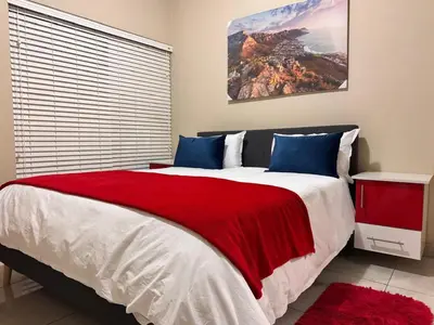 a bedroom with a large bed with a red blanket at THORNHILL ESTATE in Polokwane