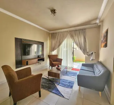 a living room with a couch and chairs and a tv at THORNHILL ESTATE in Polokwane