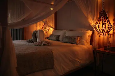 a bedroom with a white bed with a chandelier at Villa Kudu - Exclusive and Serviced Safari Villa near Kruger Park in Hoedspruit