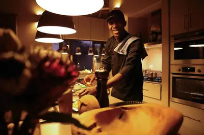 a man standing in a kitchen preparing food at Villa Kudu - Exclusive and Serviced Safari Villa near Kruger Park in Hoedspruit