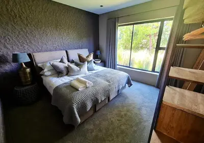 a bedroom with a bed with pillows and a window at Walkersons 96 - NinetySix on Valley View in Dullstroom