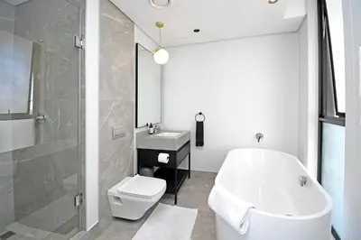 a bathroom with a tub and a toilet and a sink at Thango Res Ellipse Waterfall. in Midrand