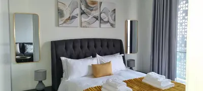 a bedroom with a bed with a black headboard and mirrors at Ellipse Waterfall City Luxury Apartment - Bigger Apartment than Most - Middle floor in Midrand