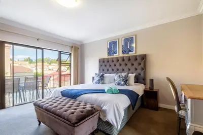 a bedroom with a large bed and a balcony at #AlimamaSpaces:The Lyndore Villa in Midrand