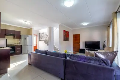 a living room with a blue couch and a kitchen at #AlimamaSpaces:The Lyndore Villa in Midrand