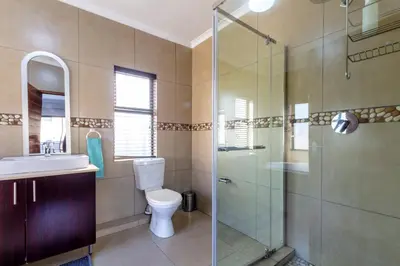 a bathroom with a shower and a toilet and a sink at #AlimamaSpaces:The Lyndore Villa in Midrand