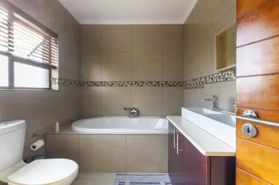 a bathroom with a tub and a toilet and a sink at #AlimamaSpaces:The Lyndore Villa in Midrand