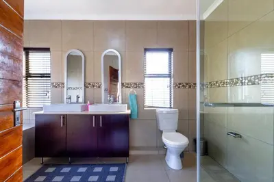a bathroom with a toilet and a sink and mirror at #AlimamaSpaces:The Lyndore Villa in Midrand