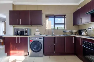 a kitchen with a washing machine and a sink at #AlimamaSpaces:The Lyndore Villa in Midrand