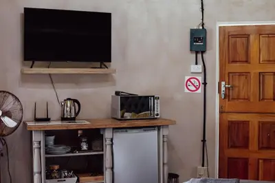 a room with a table with a television and a refrigerator at Armonia in Ermelo