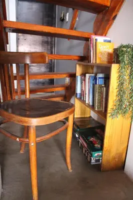 a wooden chair next to a book shelf with books at Gadute Haven - Luxury Apartment in Pretoria