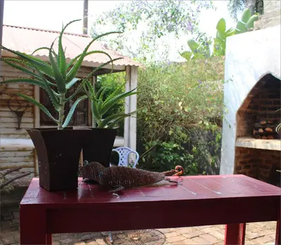 a table with a potted plant and a bird on it at Gadute Haven - Luxury Apartment in Pretoria