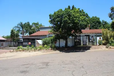 a house with a tree in front of a fence at Gadute Haven - Luxury Apartment in Pretoria