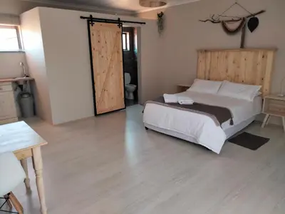 a bedroom with a bed and a sliding door at Rustic Stone Lodge in Thabazimbi
