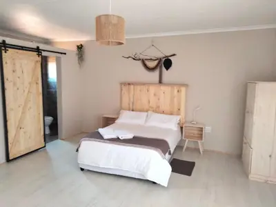 a bedroom with a large bed with a wooden headboard at Rustic Stone Lodge in Thabazimbi
