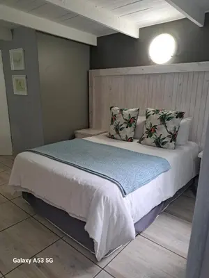a bedroom with a large white bed with pillows at eBundu Lodge in White River