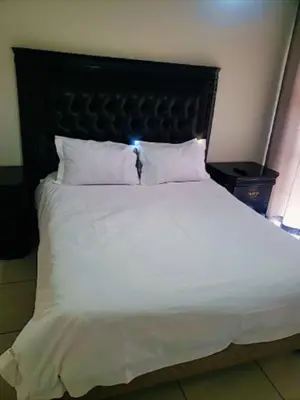 a large white bed with a black headboard and white pillows at The Blyde 1408 in Pretoria