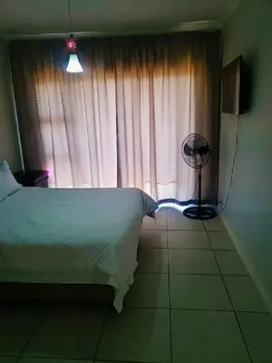 a bedroom with a bed and a window with a fan at The Blyde 1408 in Pretoria