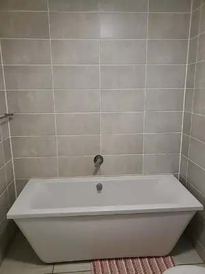 a white bath tub in a bathroom with a tile wall at The Blyde 1408 in Pretoria