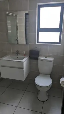 a bathroom with a toilet and a sink and a window at The Blyde 1408 in Pretoria