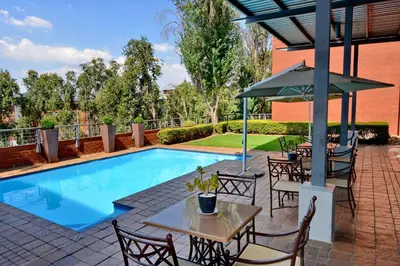 a pool with tables and chairs and an umbrella at Road Lodge Centurion in Centurion