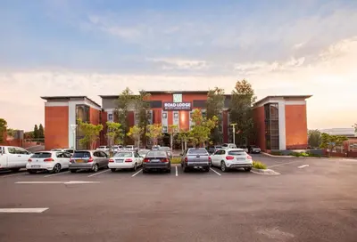 a parking lot with cars parked in front of a building at Road Lodge Centurion in Centurion