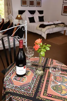 a table with a bottle of wine and a vase with flowers at Sebakwe in Dullstroom