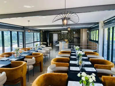 a restaurant with long tables and chairs and windows at The Anza Lifestyle Lodge in Louis Trichardt