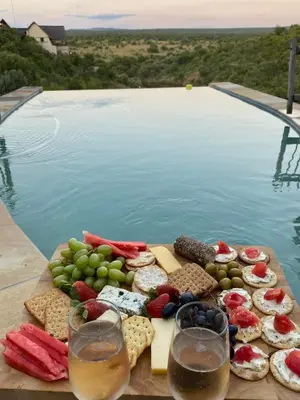 a tray of cheese and wine on a table next to a pool at Reedbuck Lodge @Cyferfontein in Mabalingwe Reserve in Bela-Bela