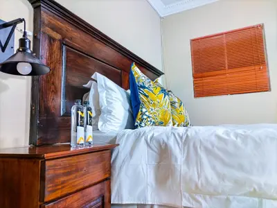 a bedroom with a white bed with a wooden headboard at Lemba Lodge in Dwarsrivier