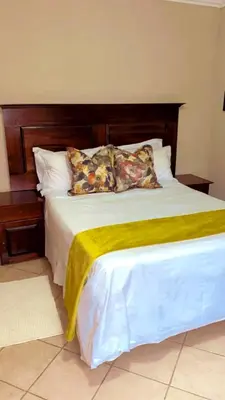 a large bed with a wooden headboard and pillows at Lemba Lodge in Dwarsrivier