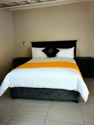 a bedroom with a large bed with an orange and white blanket at GEORGE B BOUTIQUE LODGE in Tzaneen