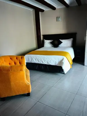a bedroom with a bed and a chair in it at GEORGE B BOUTIQUE LODGE in Tzaneen