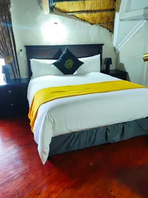 a bedroom with a large bed with yellow and white sheets at GEORGE B BOUTIQUE LODGE in Tzaneen