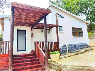 a small white house with a red deck at GEORGE B BOUTIQUE LODGE in Tzaneen