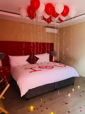a bedroom with a bed with red and white balloons at GEORGE B BOUTIQUE LODGE in Tzaneen
