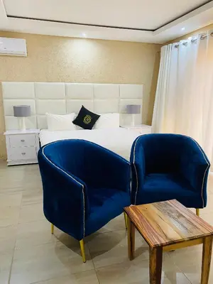 a bedroom with a bed and two blue chairs at GEORGE B BOUTIQUE LODGE in Tzaneen
