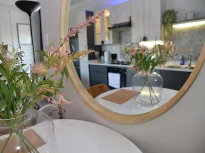 a mirror sitting on a table with flowers in vases at Eirini Elegant - Ares Apartment Carlswald in Midrand