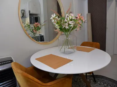 a vase of flowers on a table in front of a mirror at Eirini Elegant - Ares Apartment Carlswald in Midrand