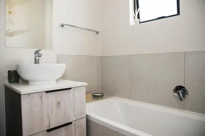 a bathroom with a white tub and a sink at Eirini Elegant - Ares Apartment Carlswald in Midrand