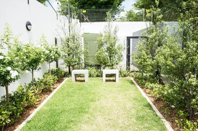 a garden with two benches in the grass at Eirini Elegant - Ares Apartment Carlswald in Midrand