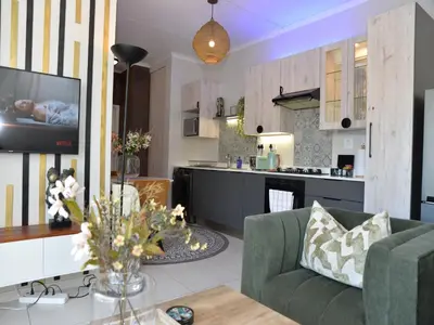 a living room with a couch and a kitchen at Eirini Elegant - Ares Apartment Carlswald in Midrand