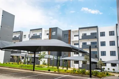 an umbrella in a parking lot in front of a building at Eirini Elegant - Ares Apartment Carlswald in Midrand