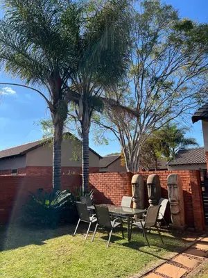 a table and chairs in a yard with two statues at Centurion Ambient Townhouse in Centurion