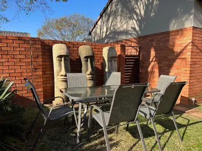 a table and chairs in front of a brick wall at Centurion Ambient Townhouse in Centurion